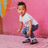 A toddler getting ready to jump in a pair of gray Emerson  children's barefoot shoe by Jack & Lily