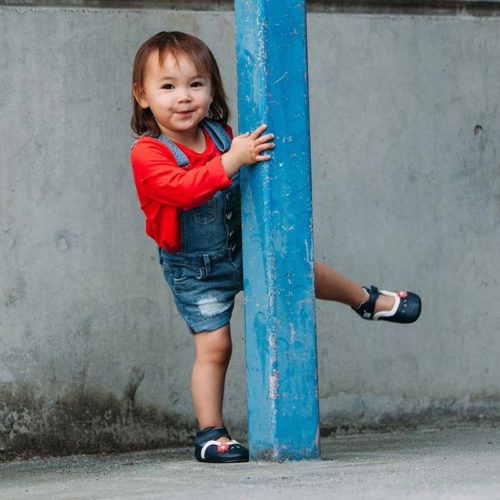 A toddler having fun wearing a blue pair of Charlotte children's barefoot shoes by Jack & Lily
